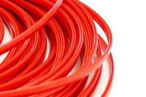 Red bottle neck guides in a coiled configuration, crafted from FDA-approved UHMW material, designed for bottling conveyor systems to enhance speed and durability.